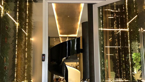 A modern interior with a curved staircase, glass walls, and decorative lighting.