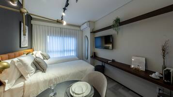 A hotel room with a bed, bedside table, and a dining area with a table set for two.