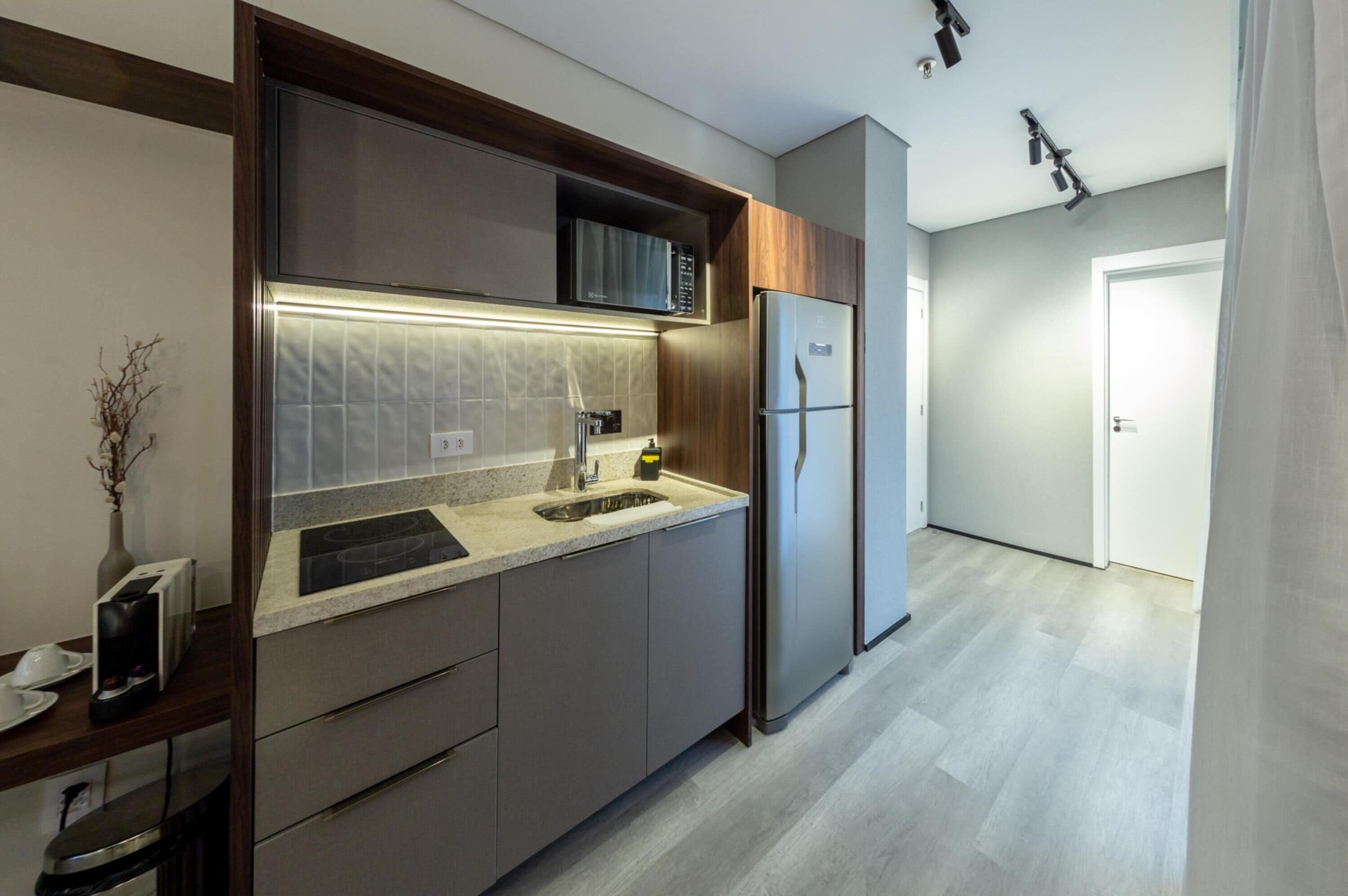 Una cocina moderna con microondas integrado, refrigerador de acero inoxidable y encimera de granito.
