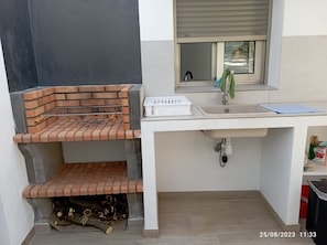 A compact kitchen with a built-in brick oven, a sink, and a window above it.