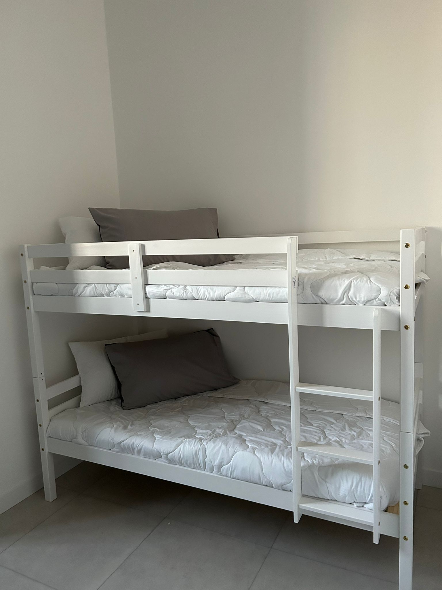 Una cama litera con tres niveles, cada uno con almohada y ropa de cama blanca.