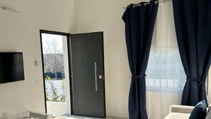 Ein modernes Wohnzimmer mit einer Couch, einem Esstisch mit Stühlen und einer schwarzen Tür, die nach draußen führt.