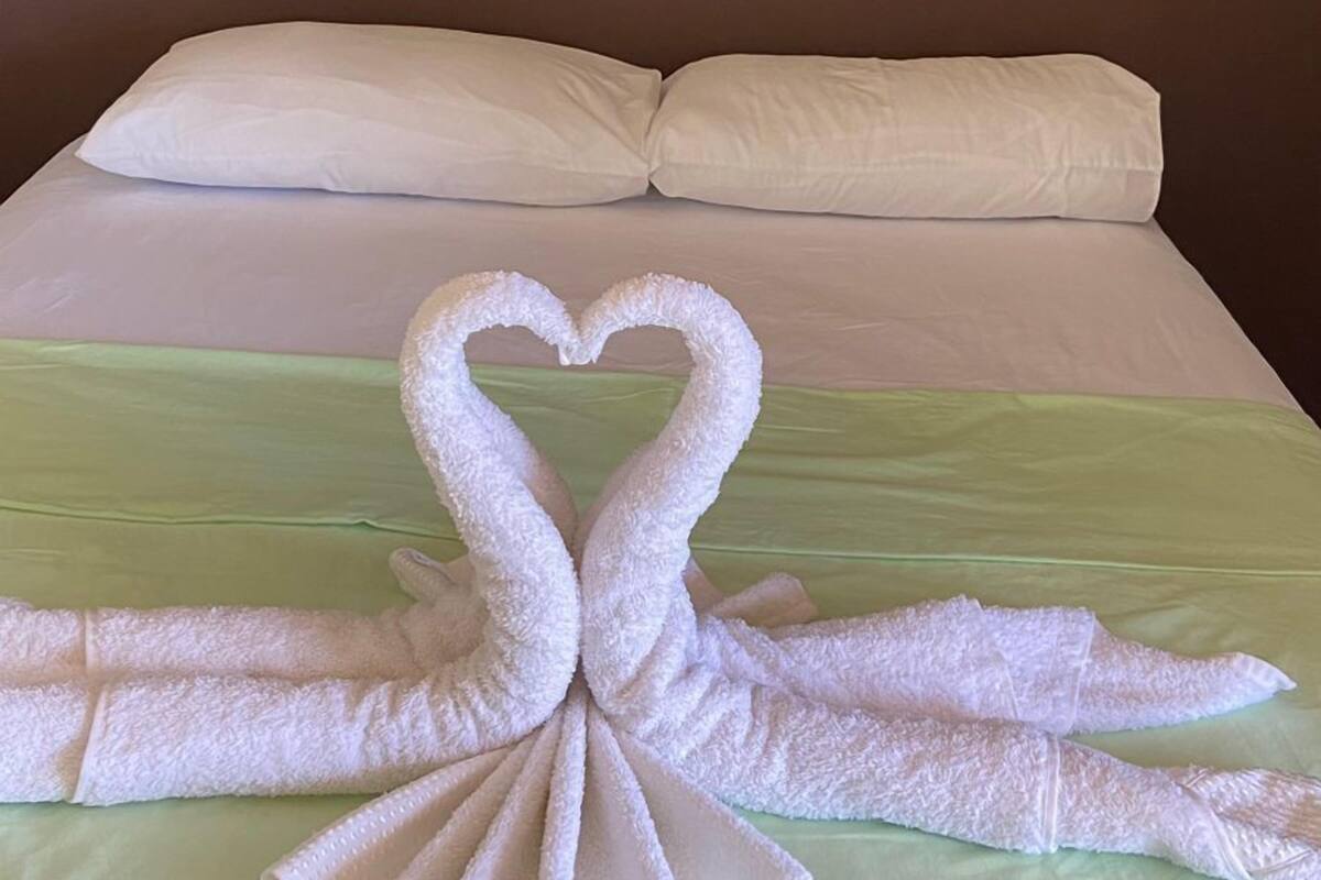 A bed with a heart-shaped towel arrangement on the bedspread.