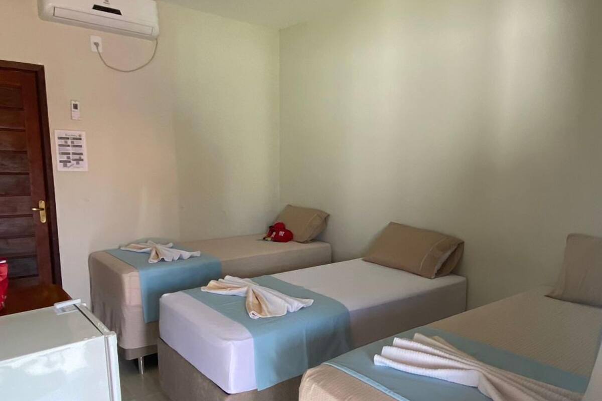 A small, clean room with two single beds, a small table, and a refrigerator.