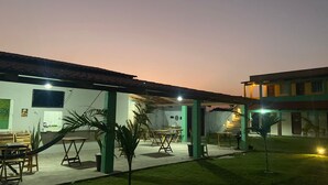 Ein Außenbereich mit Terrassentischen und -stühlen, ein kleiner Garten und ein Gebäude mit einem Ziegeldach.