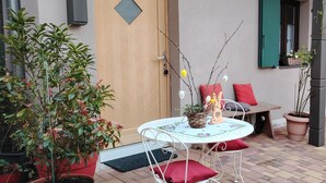 A patio with a round table, chairs, and potted plants. - Appartement Le Marly (Dambach-la-ville)