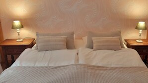 A double bed with a white duvet, two bedside tables with lamps, and a patterned wall. - Appartement Le Marly (Dambach-la-ville)