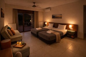 A hotel room with a bed, two bedside tables with lamps, a sofa, a coffee table with glasses and a tray, and a view through a glass door.