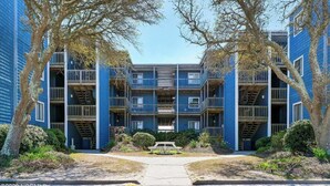 Un immeuble à plusieurs étages, doté de balcons et d’une entrée centrale.