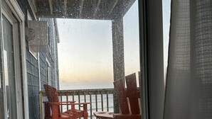 Un balcon avec vue sur l’océan, des chaises en bois et une balustrade.