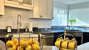 A kitchen with a wire basket of lemons, a yellow mug rack, and a stainless steel sink. - River Access, hot tub, dogs! (Conway)