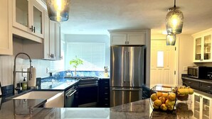 A modern kitchen with stainless steel appliances, a marble countertop, and pendant lighting. - River Access, hot tub, dogs! (Conway)