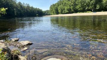 Ein Fluss mit klarem Wasser, umgeben von Bäumen und Felsen.