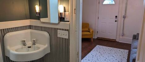 A bathroom with a white sink, a mirror, and a shower area.