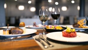A dining table with plates of food and wine glasses.