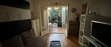 Una sala de estar con un sofá, una mesa de centro, un televisor y un ventanal corredizo que da a un espacio al aire libre.