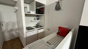 Eine kompakte Küche mit eingebautem Geschirrspüler, einer kleinen Spüle und einer Mikrowelle.