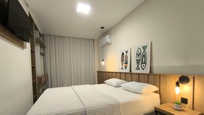 A neatly arranged bedroom with a bed, bedside table, and wall-mounted artwork. - Refúgio Praiano (Bombinhas)