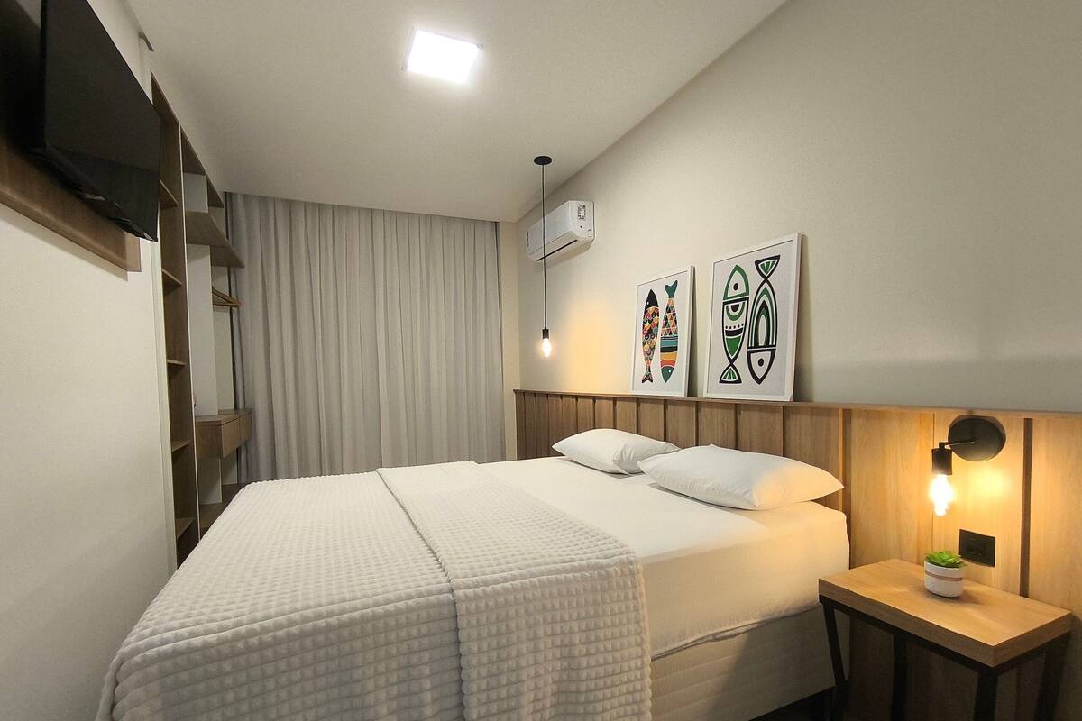 A neatly arranged bedroom with a bed, bedside table, and wall-mounted artwork.