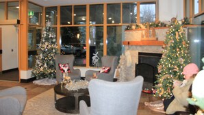 A spacious room with large windows, a fireplace, and multiple Christmas trees. - Cascade Lodge suite ski/bike storage room WIFI pool 2 hot tub sauna gym cable TV (Whistler)