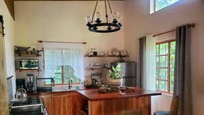 A kitchen with wooden cabinets, a central island, a chandelier, and a refrigerator.