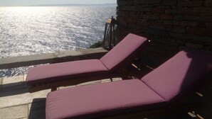 Two purple lounge chairs on a stone deck overlooking a body of water. - Waterfront Villa with private swimming pool-walking distance to a sandy cove. (Kea)