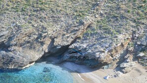 A coastal landscape with rocky terrain and a clear blue sea. - Waterfront Villa with private swimming pool-walking distance to a sandy cove. (Kea)