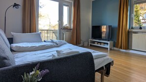 Un dormitorio con cama, televisión y ventana con cortinas.