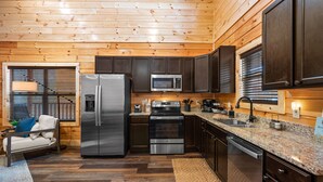 A modern kitchen with wooden paneling, stainless steel appliances, and a granite countertop.