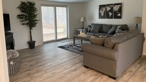 A modern living room with a grey sofa, a coffee table, a potted plant, and a television. - Cozy Country home just 5 miles to Boyne City/8 miles to Boyne Mountain (Boyne City)