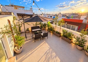 A rooftop patio with a seating area, potted plants, and a view of the cityscape. - At the Palazzotto (Fasano)