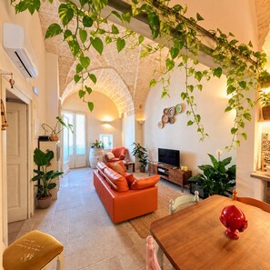 A living room with a sofa, television, and plants. - At the Palazzotto (Fasano)