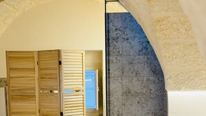 Une pièce avec un mur en pierre, une porte en bois et un sol carrelé.