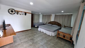 A hotel room with two single beds, a wooden desk, a TV, and a wall-mounted hat rack.