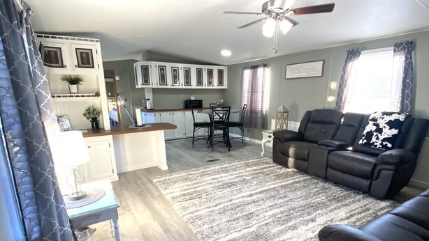 A spacious living room with a large sectional sofa, a dining area with a table and chairs, and a kitchen area with cabinets and appliances. - Della’s Delight- Sleeps 4 (Campbellsville)