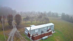 A two-story house with a fenced yard, a covered porch, and a satellite dish. - Della’s Delight- Sleeps 4 (Campbellsville)