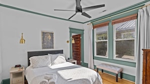 Ein Schlafzimmer mit Bett, Nachttisch, Lampe und Fenster.