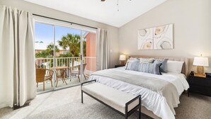 Ein Schlafzimmer mit einem großen Bett, einem Deckenventilator, einem Nachttisch, einer Bank und Blick ins Freie.