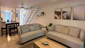 A living room with two sofas, a coffee table, a staircase, and a dining area.