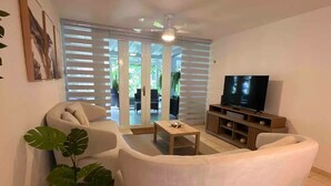 A living room with a sofa, a coffee table, a television, and a potted plant.