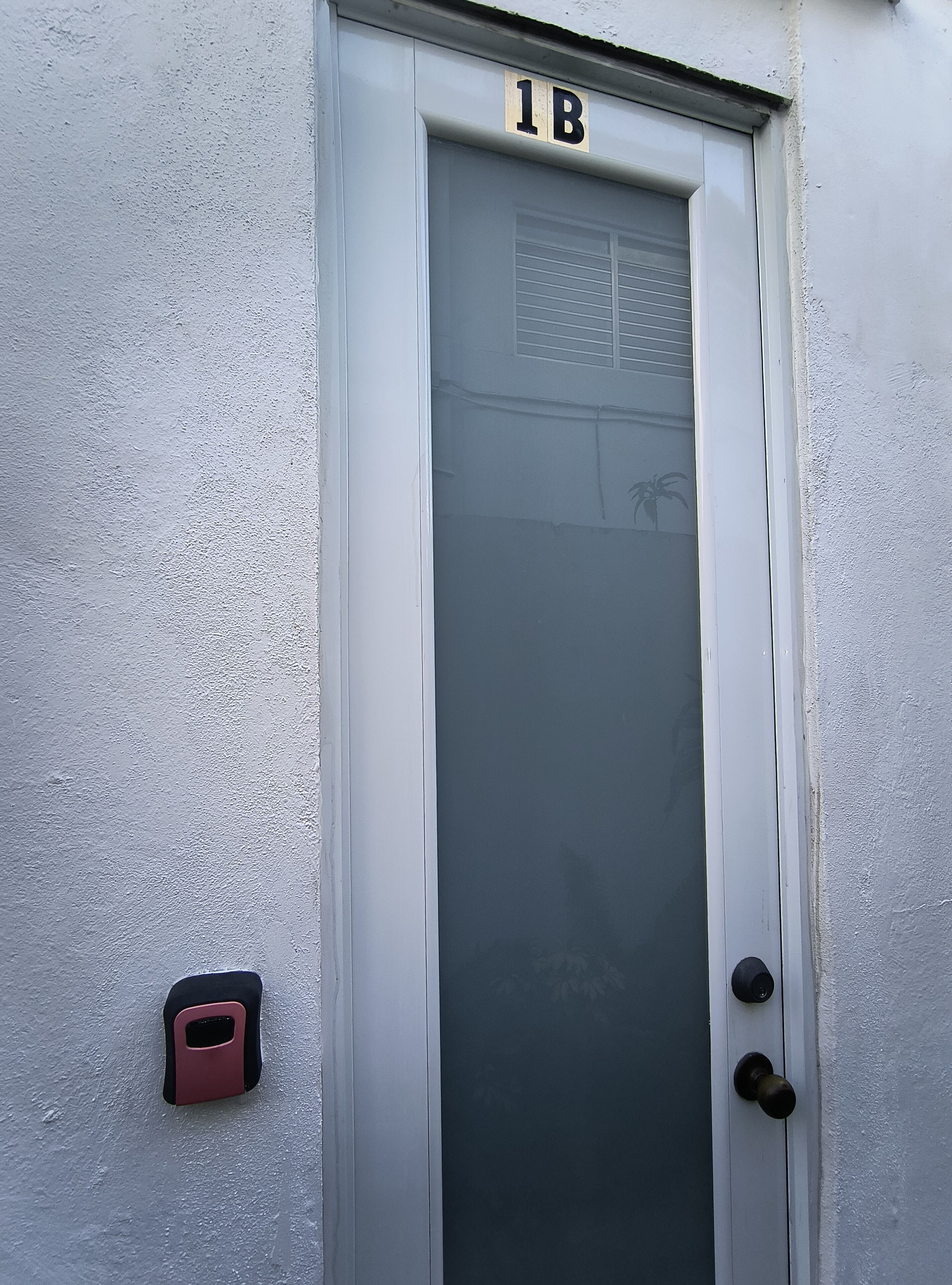 A white door with a frosted glass panel and a number plate indicating '1B'.