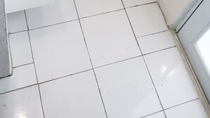 Uma casa de banho pequena e limpa, com sanita branca, lavatório e um esfregão azul.