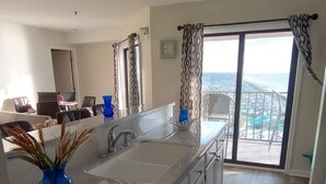 A modern kitchen with a large island, a sink, and a view of a balcony. - Oceanfront 2B/2B family sized condo (Myrtle Beach)