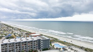 A beachfront hotel with multiple floors, a swimming pool, and a beach view. - Oceanfront 2B/2B family sized condo (Myrtle Beach)