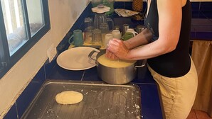 Een keuken met een raam, een pan op het aanrecht en diverse keukengerei.