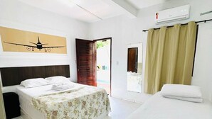 Quarto de hotel com duas camas, uma janela grande, ventilador de teto e ar condicionado.