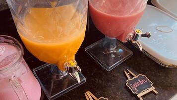 En juicebar med två stora behållare, en orange och en rosa, samt en mindre rosa behållare.