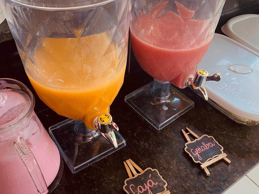 En juicebar med två stora behållare, en orange och en rosa, samt en mindre rosa behållare.