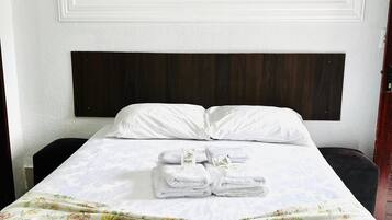 A hotel room with a bed, a headboard, a wall-mounted airplane painting, and a floral bedspread.
