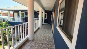 Un pasillo cubierto con suelo de baldosas, barandillas blancas y vistas al exterior.